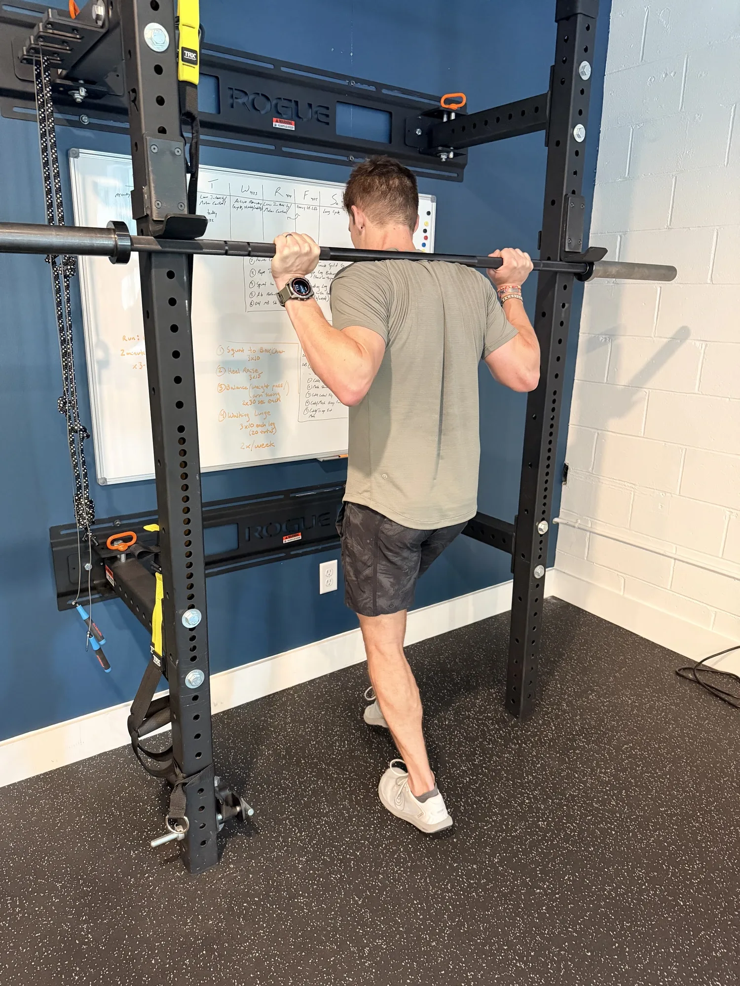 Dr. Hunter Pickens, PT, DPT loading the calf and Achilles with a barbell in a squat rack, the same setup used for high-intensity calf isometric holds, at Swamp Rabbit Physiotherapy in Greenville, SC