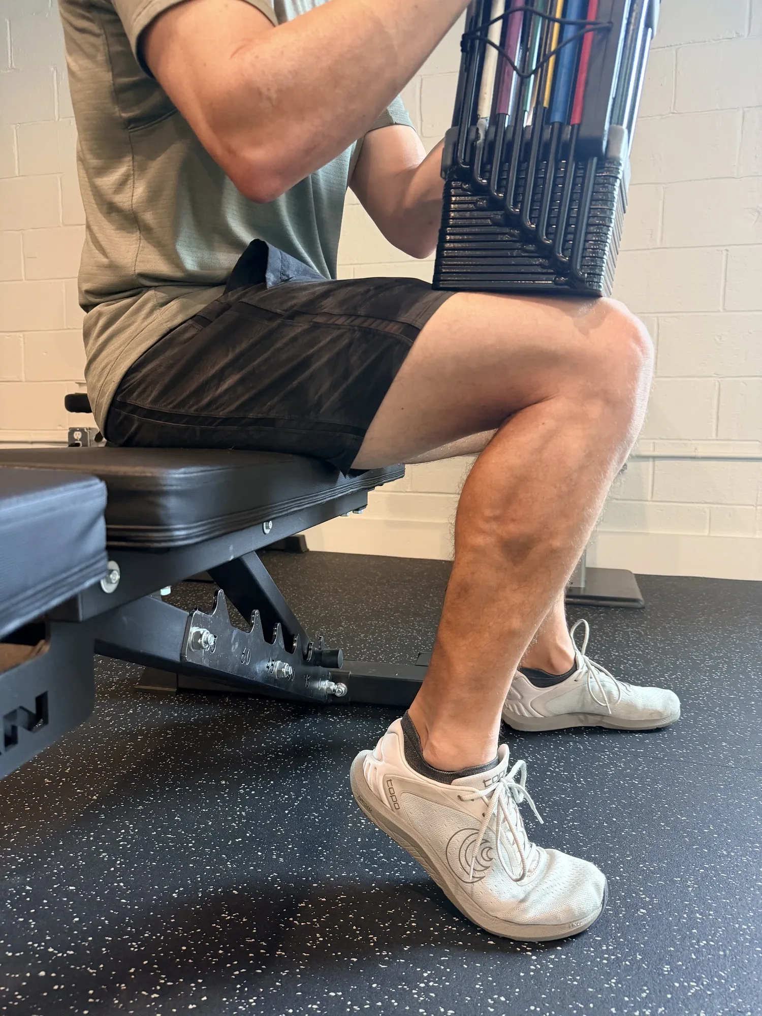 Bent-knee seated calf raise with dumbbells resting across the thighs, a soleus-biased exercise for runners, at Swamp Rabbit Physiotherapy in Greenville, SC